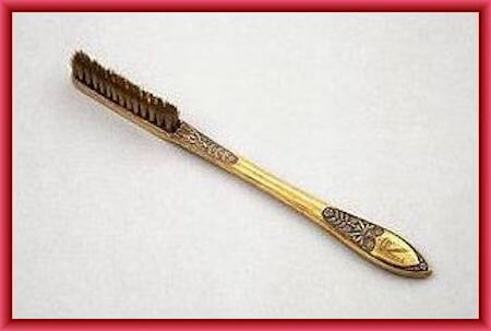 ornate golden vintage toothbrush with a long brushing head
