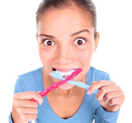 woman brushing her teeth with two toothbrushes