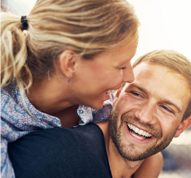 Dental Crowns patient model smiling with his wife on his back