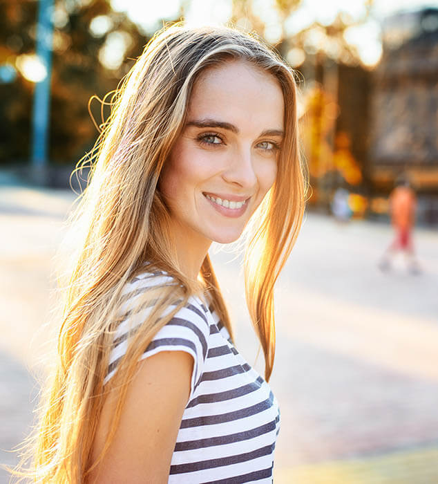 blond root canal patient model in a striped shirt smiling