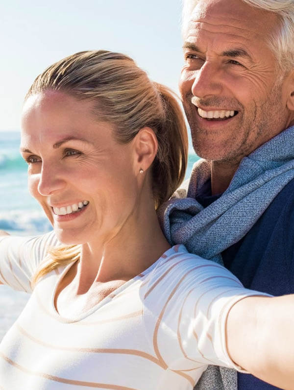 dental implants and dentures patient models embracing at the beach