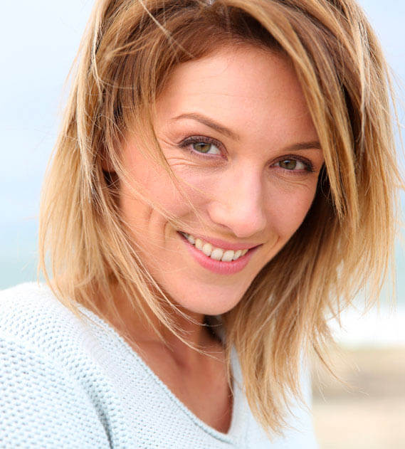 full Mouth Reconstruction patient model smiling in a white shirt