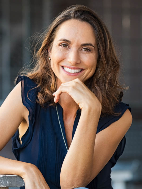 Dental Crowns patient model smiling broadly wearing a blue blouse